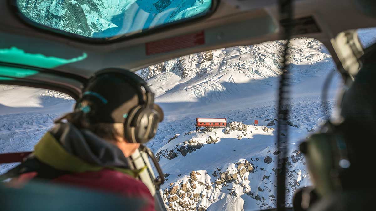 helicopter hovering over snow-capped mountains