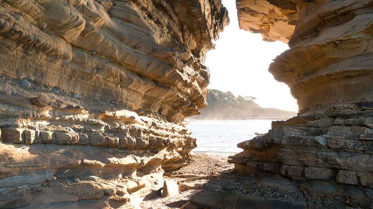 Light coming through opening in rocks on the beach