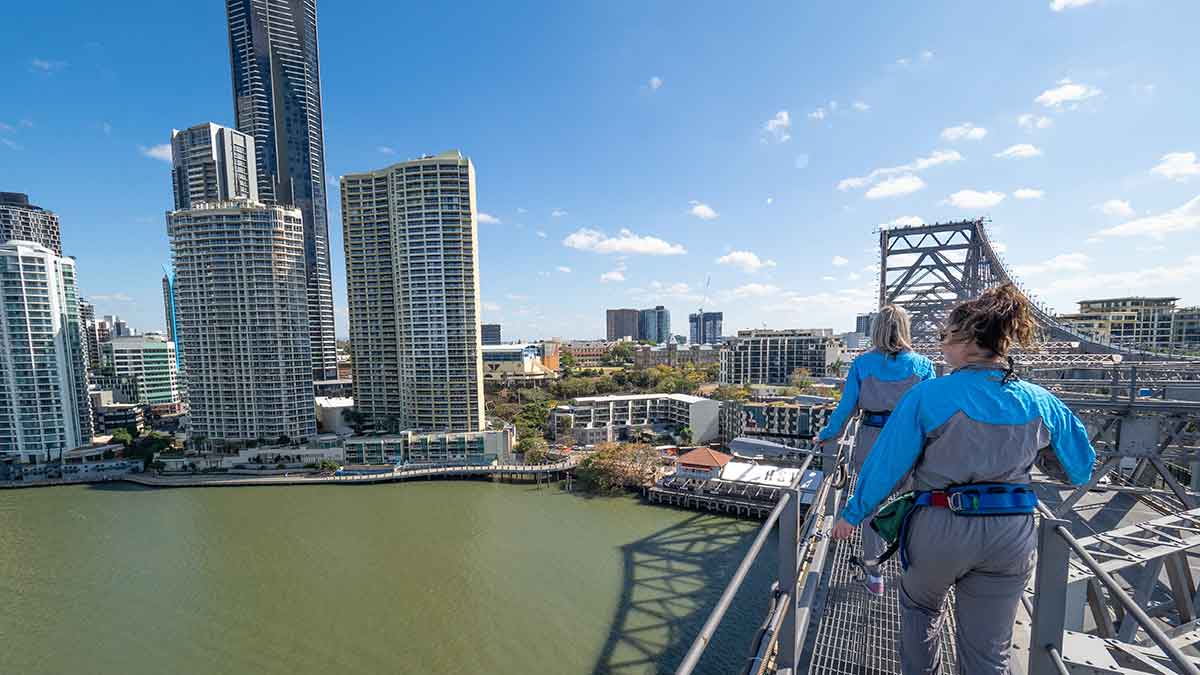 People walking across a bridge with city skyline in the background