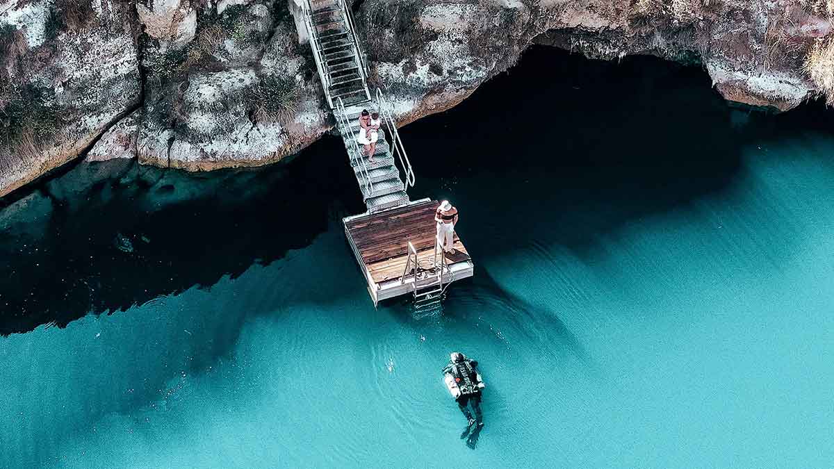 snorkeling in crystal blue waters while two people stand on the jetty