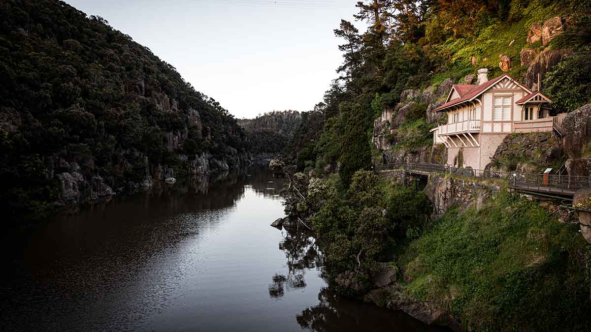 A house perched on the cliff with a river running underneath. 