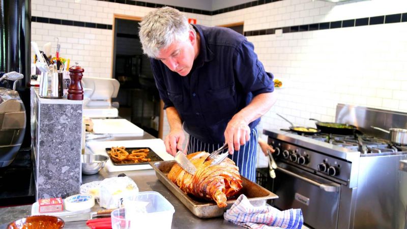 man carving pork in a commercial kitchen