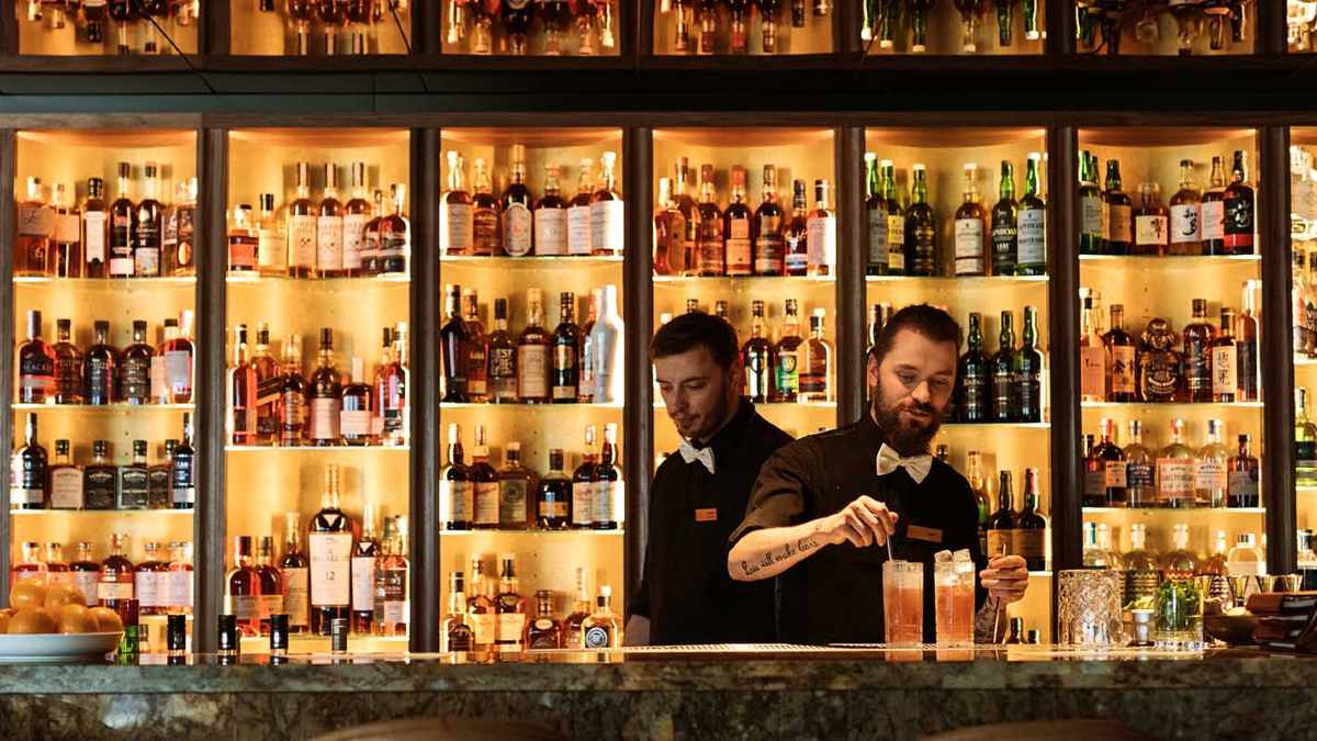 Bartenders in front of shelves with drinks