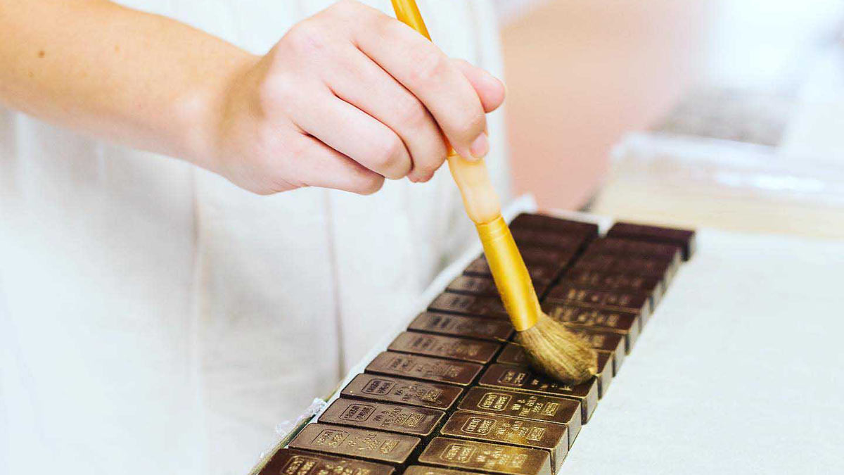 Person dusting chocolate with gold specks