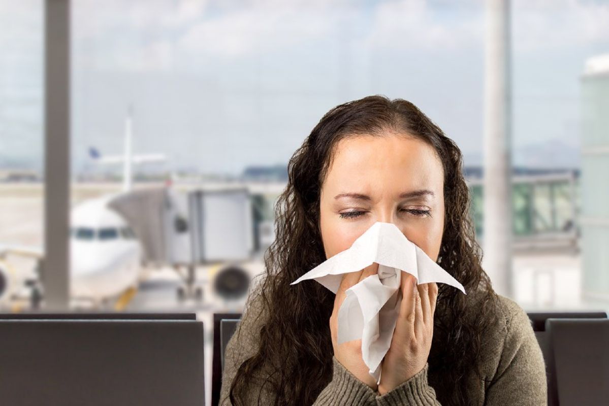 Woman blowing nose in airport