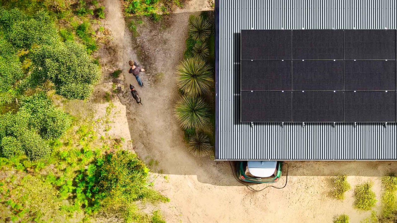 aireys-case-study-5-hero-1600x900.jpg RACV installed Solar Panels and a car being charged by an EV battery in an aerial view of a house in Aireys Inlet