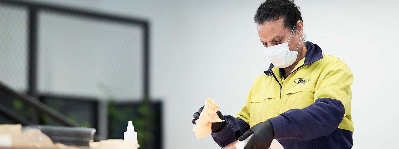 Man with face mask cleaning with a cloth.