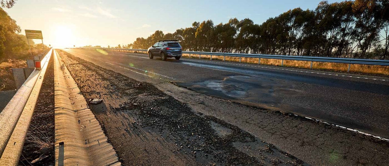 Car travelling on road with uneven surface