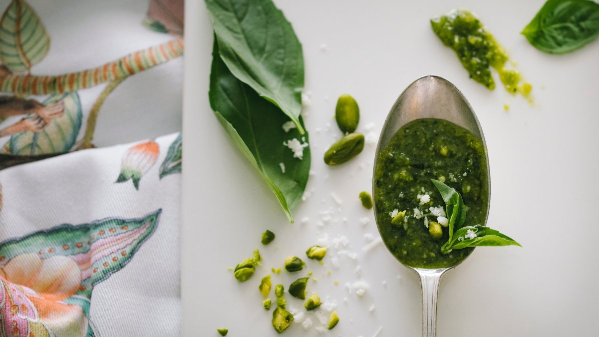 spoonful of pesto on chopping board surrounded by ingredients