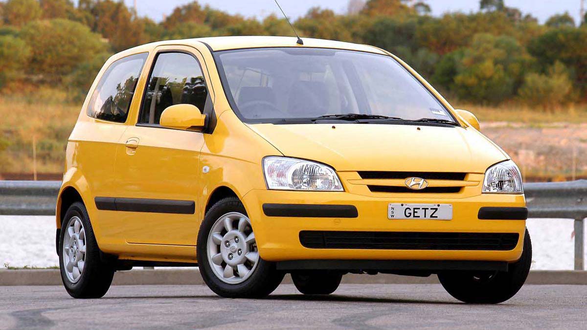 Front side view of a yellow Hyundai Getz parked on a road next to a river