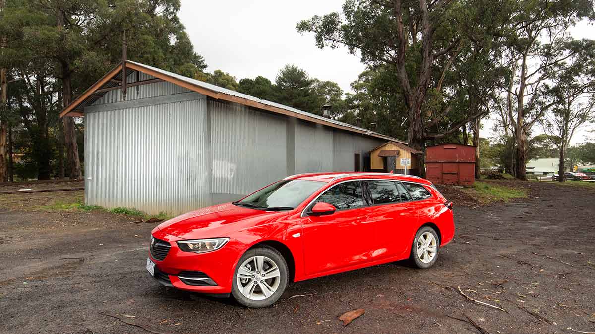 Red Holden Commodore parked in front of a shed