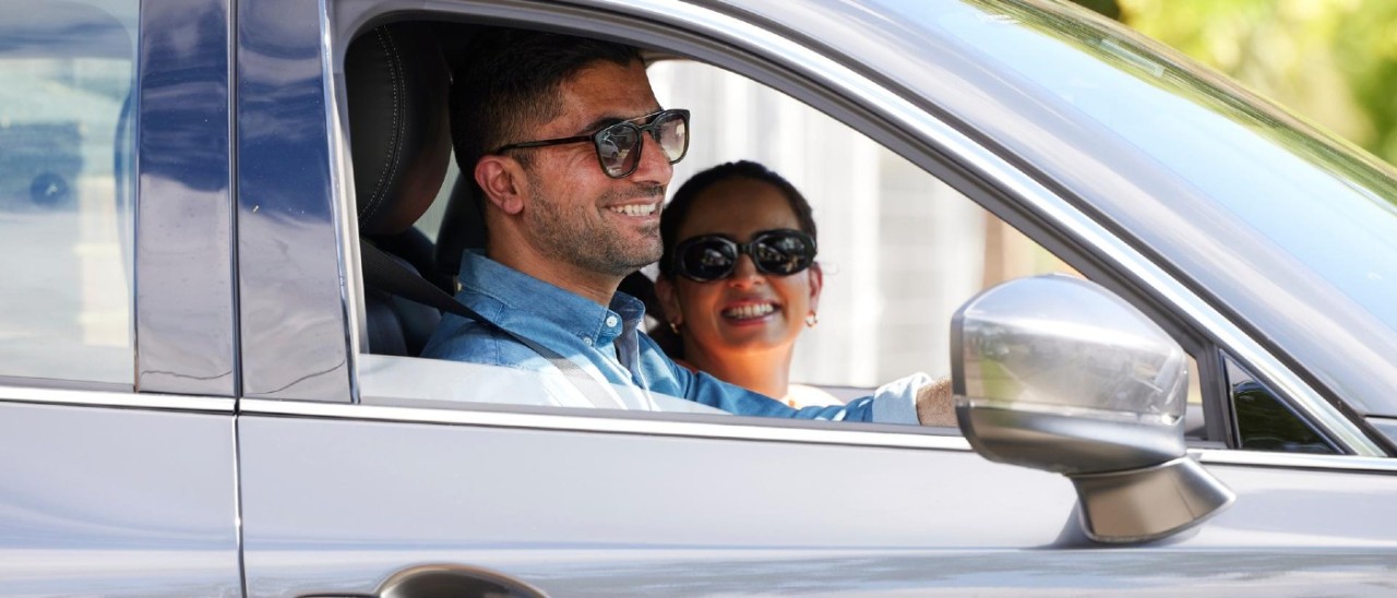 Couple in car A man and a woman wearing sunglasses and smiling in a car