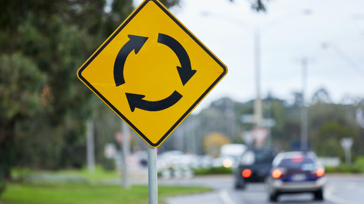 A roundabout sign by a road