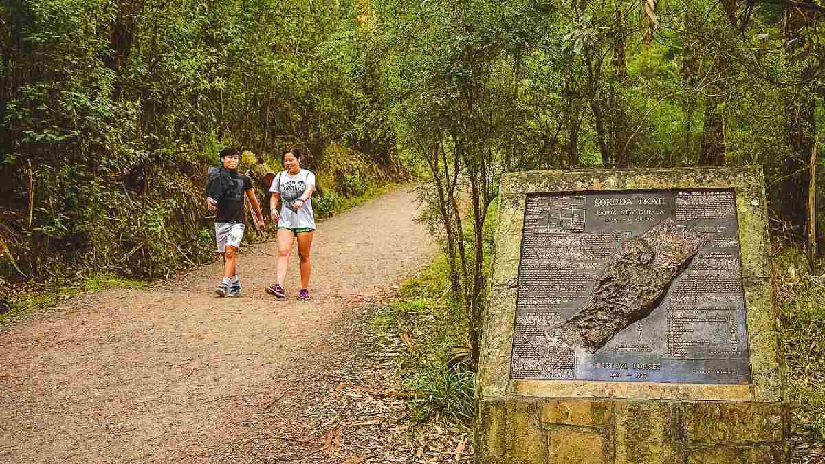 Couple walks past Kokoda Memorial Walk sign
